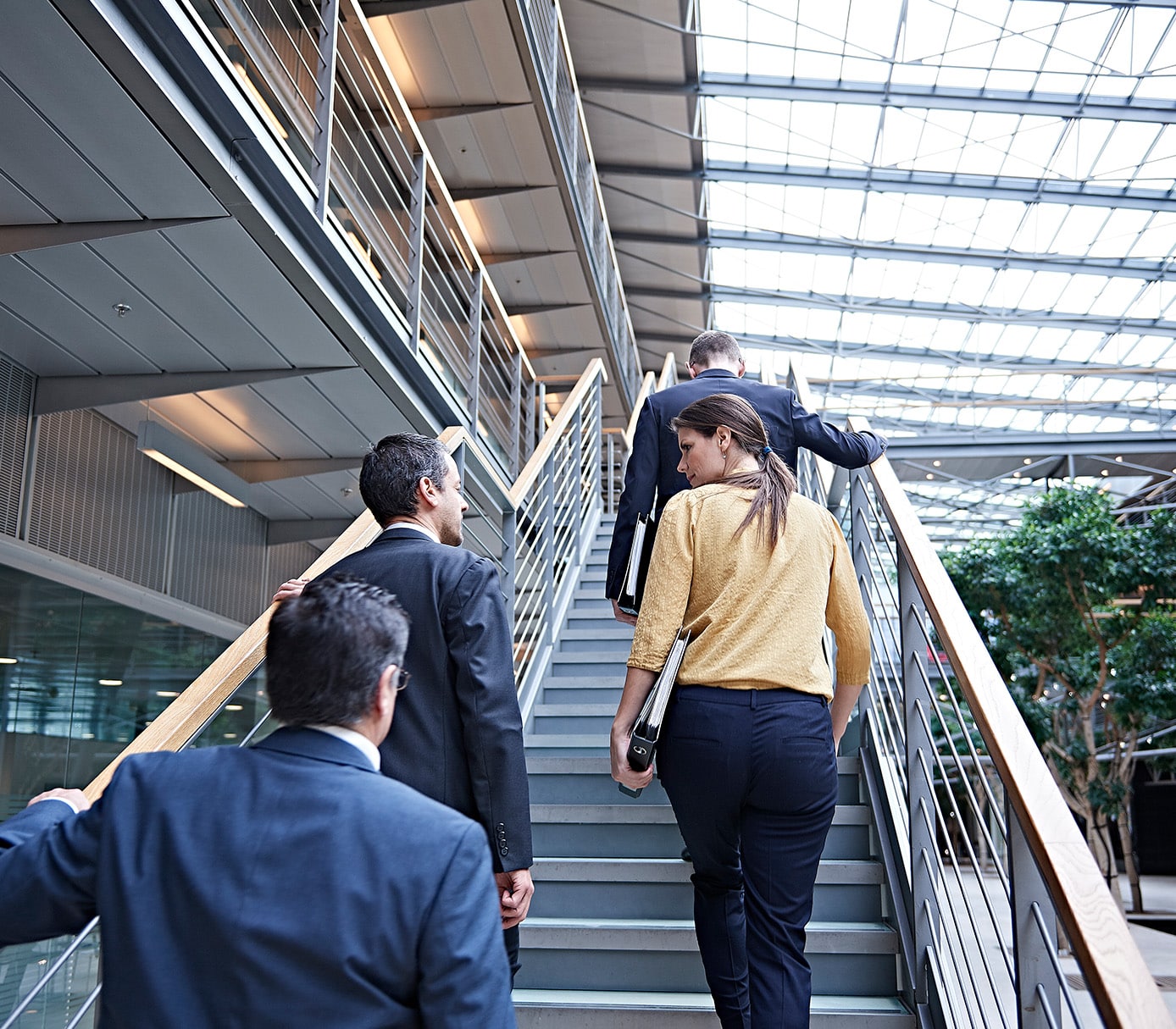 rear view of businesswoman and men moving up office